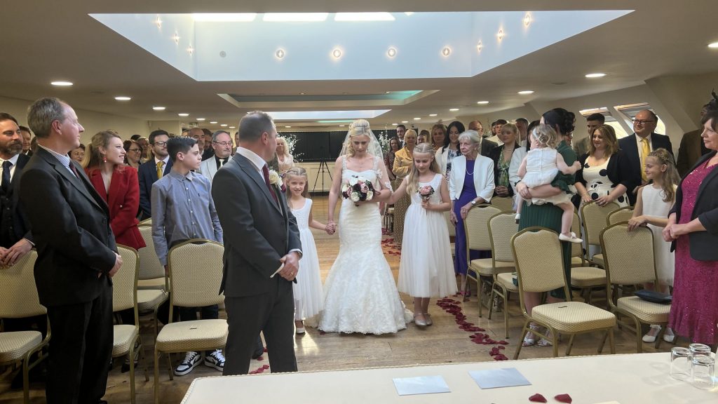 Bride walking down the aisle with guests standing during indoor wedding ceremony